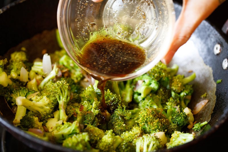 adding soy sauce and seasonings to the broccoli