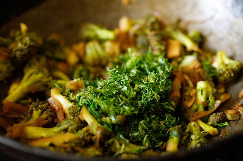 adding fresh herbs to broccoli stir fry