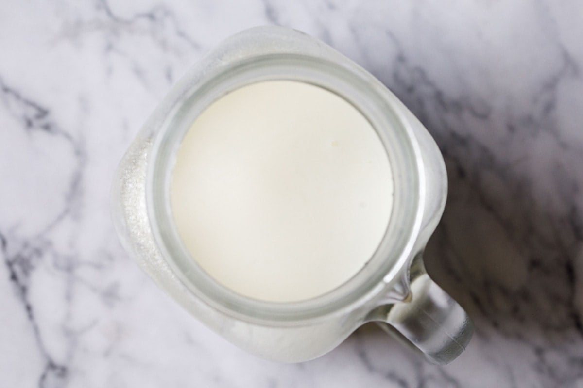 top shot of buttermilk in a glass jar with handle on marble board