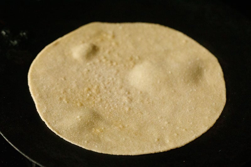 rolled chapati dough on black iron tawa