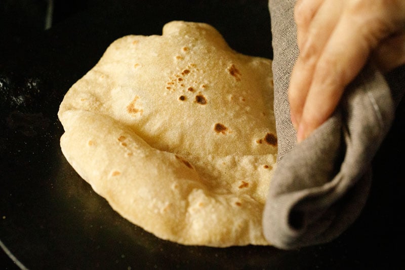 chapati being puffed by pressing with cotton napkin