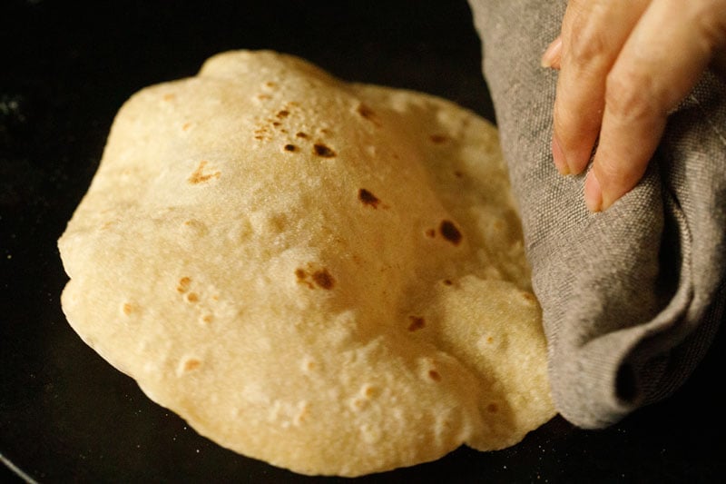 chapati being puffed by pressing with cotton napkin