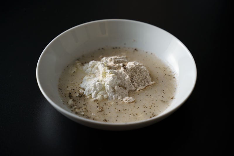 water added to flour mixture in white bowl