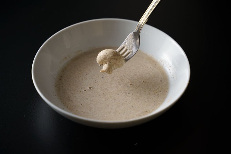 mushroom coated with batter and lifted with a fork