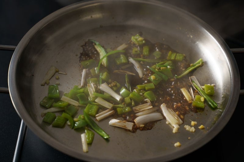 soy sauce bubbling on skillet with the aromatic and herbs