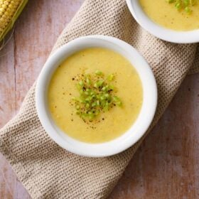 corn soup in white bowl garnished with spring onion greens