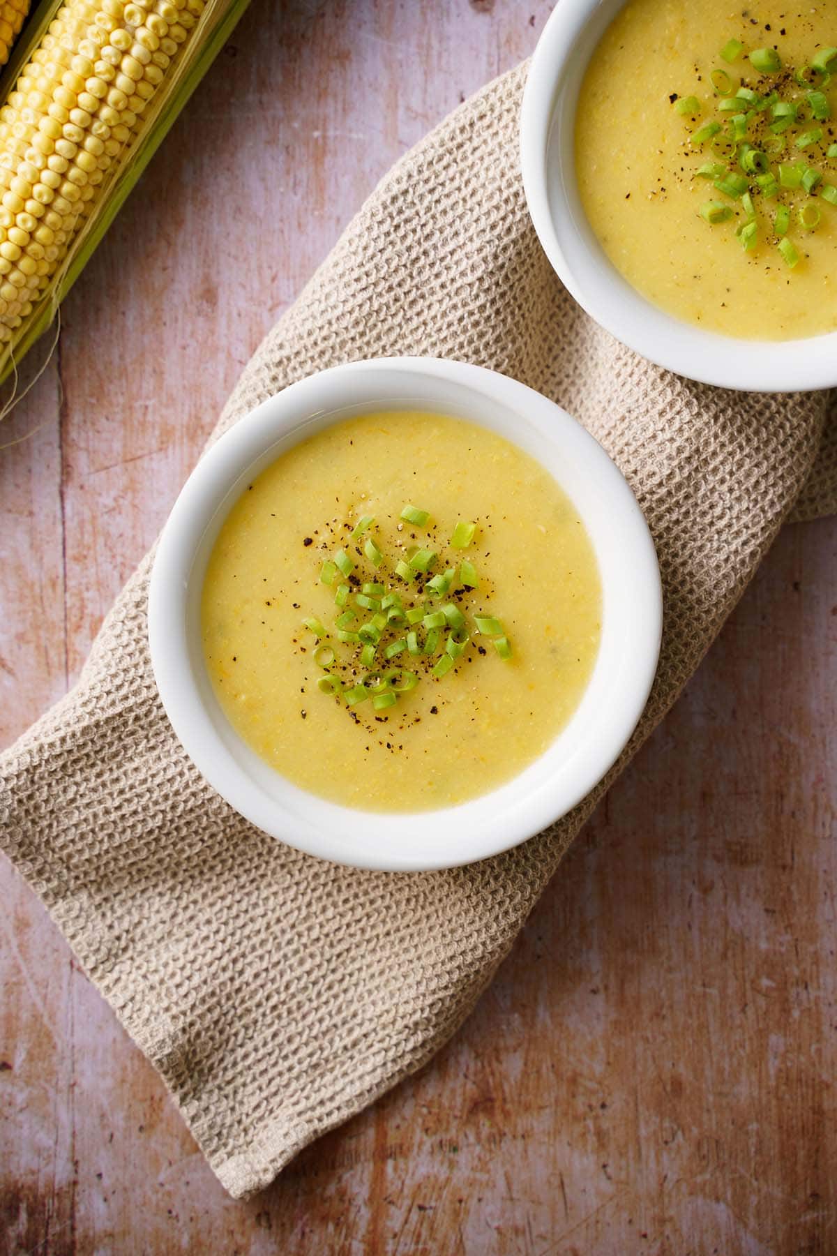 corn soup in white bowl garnished with spring onion greens