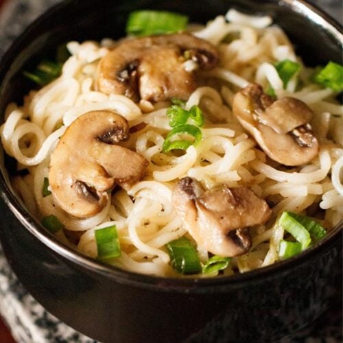 mushroom noodles with scallion greens in black bowl