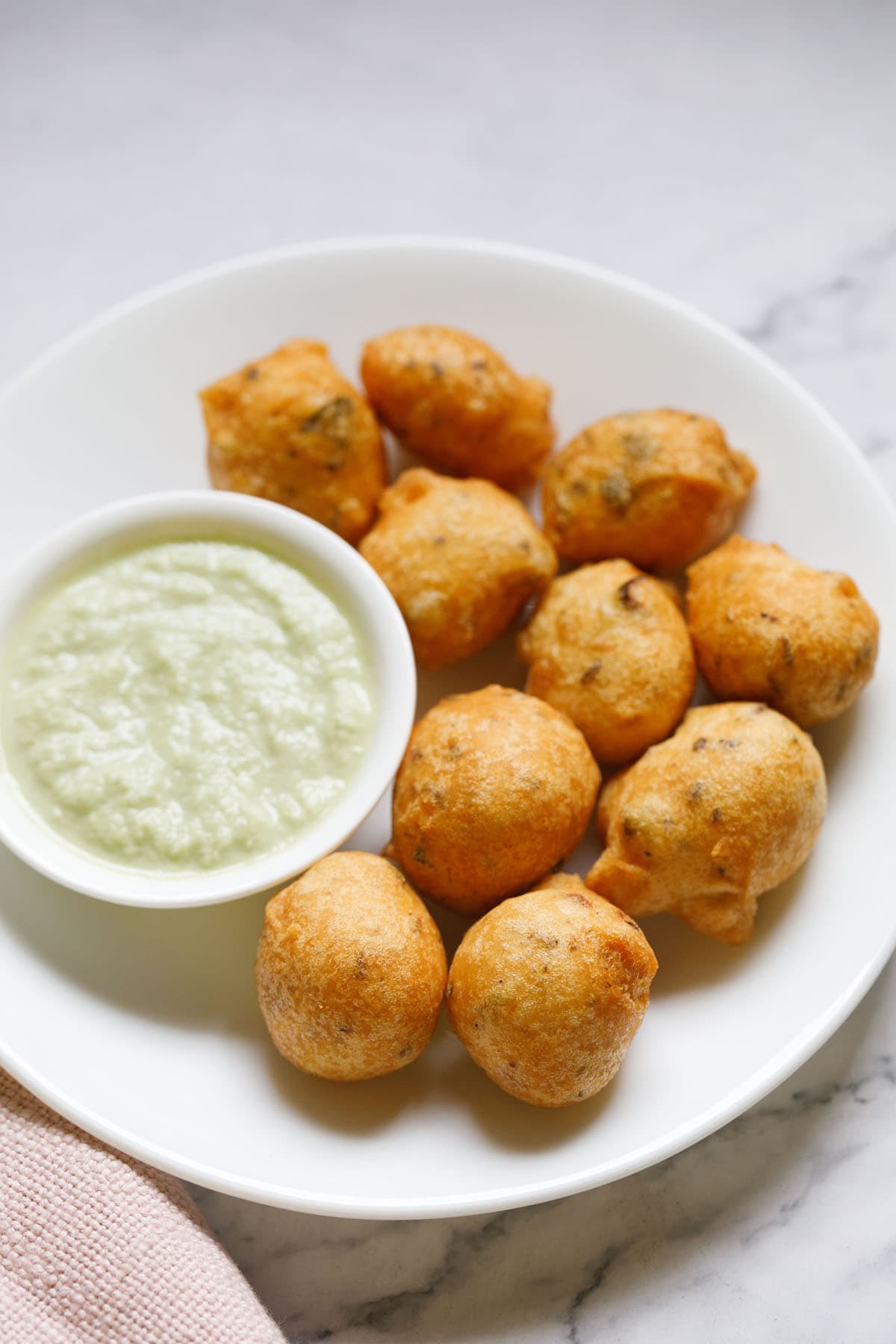 mysore bajji in white plate next to a small bowl of coconut chutney