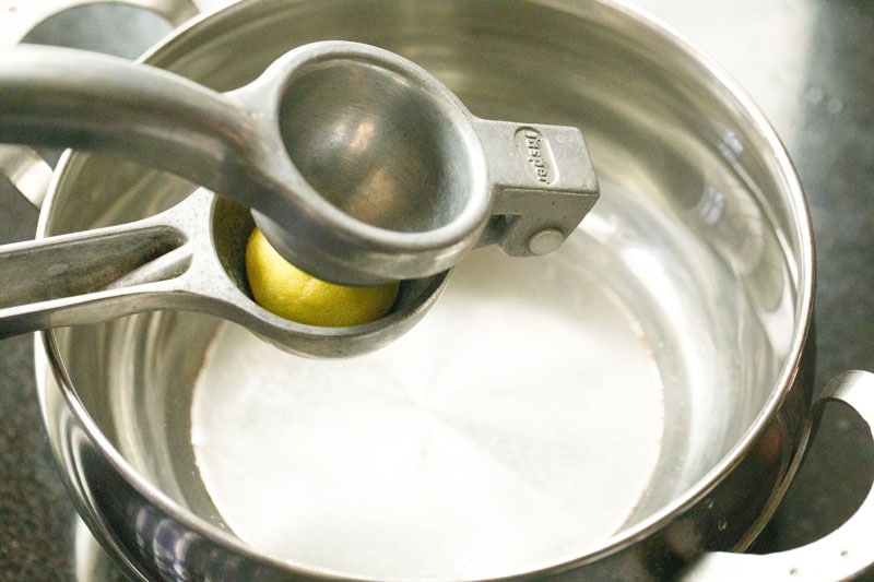 using a citrus press to squeeze half of a lemon
