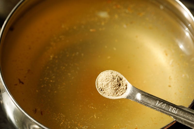 white pepper powder being added to shikanji or nimbu pani as flavoring