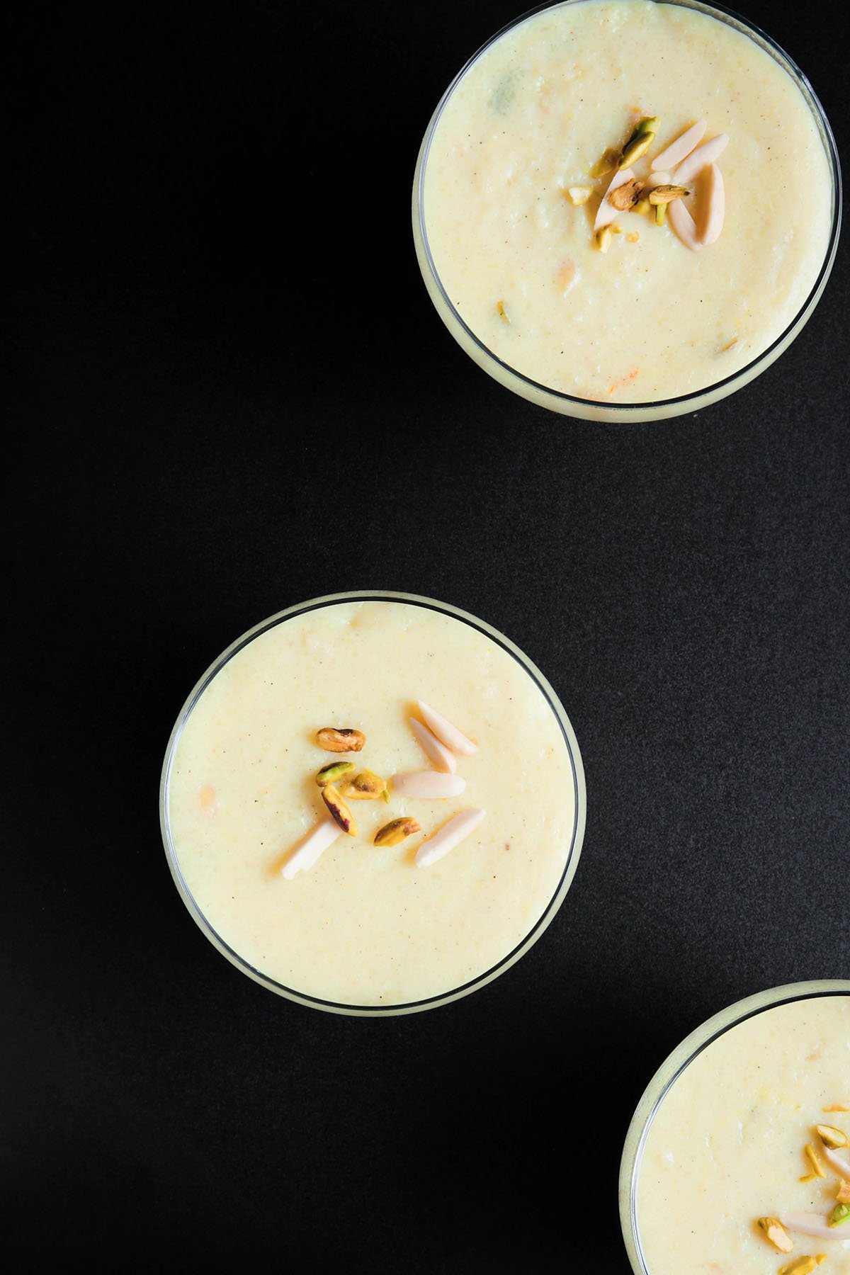 overhead shot of phirni in glass bowls on black board