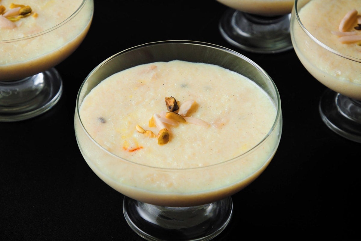 closeup shot of phirni in glass bowls with stems on black board