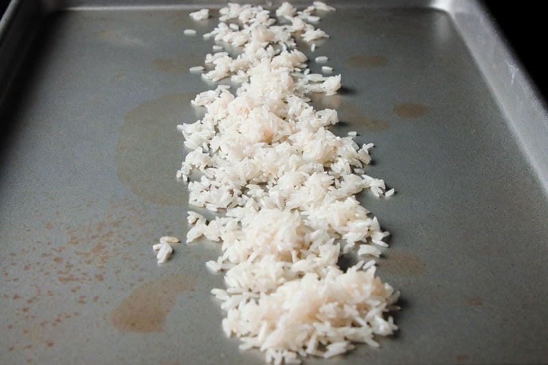 una sola capa de arroz enjuagado en una bandeja de metal plateado