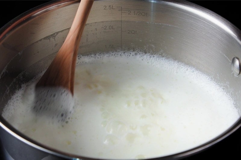 stirring milk in pan with wooden spoon