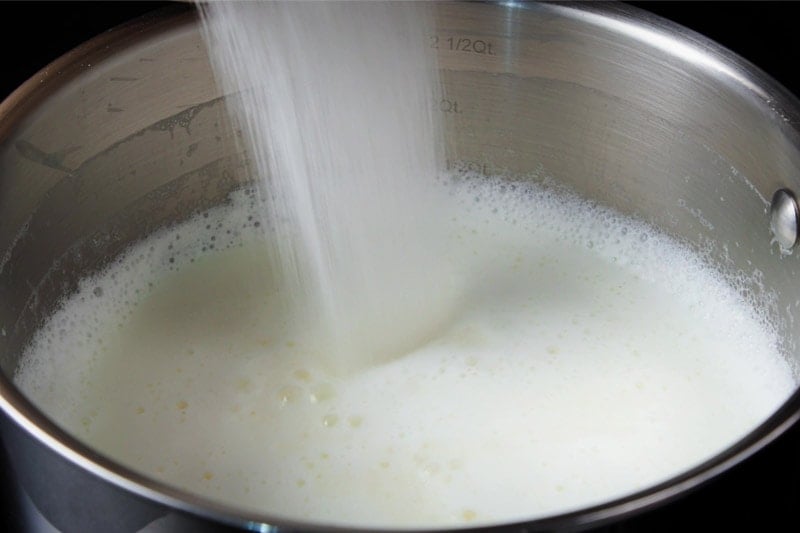 sugar being added to the milk in pan