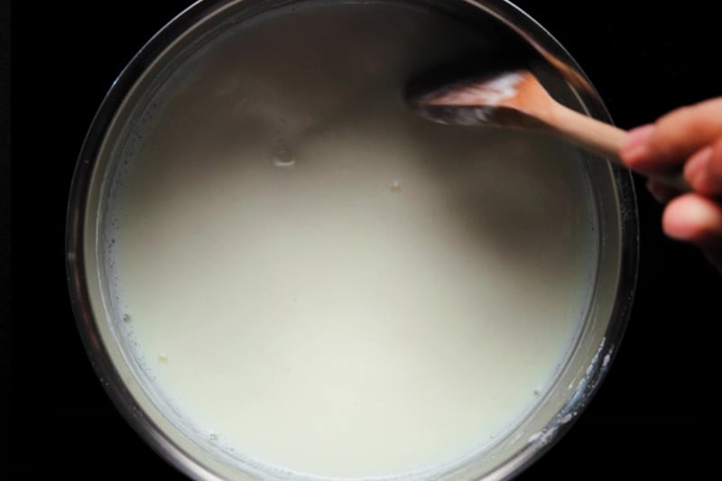 stirring milk in pan with a wooden spoon