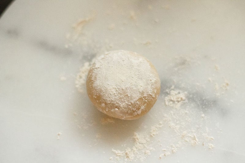 dough ball on a white marble board that has been sprinkled with flour for rolling