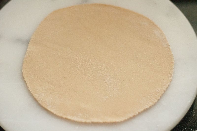 raw phulka dough on a marble slab after rolling out