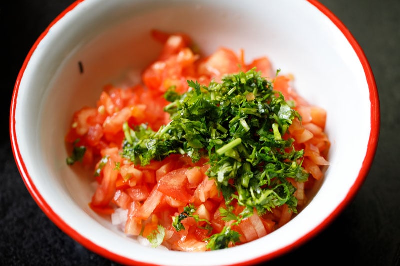 tomatoes and cilantro added to mixing bowl with onions, chiles and garlic