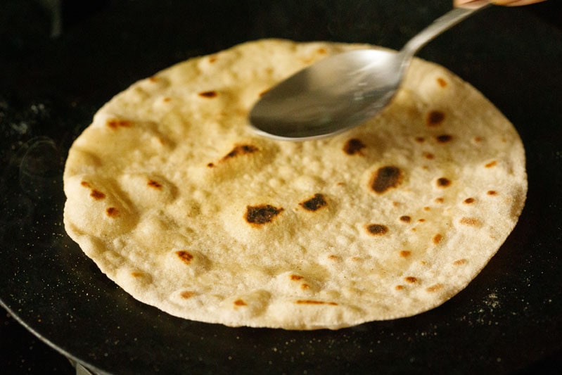 oil being spread on this side of chapati