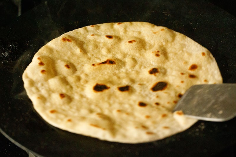 pressing edges of chapati with spatula