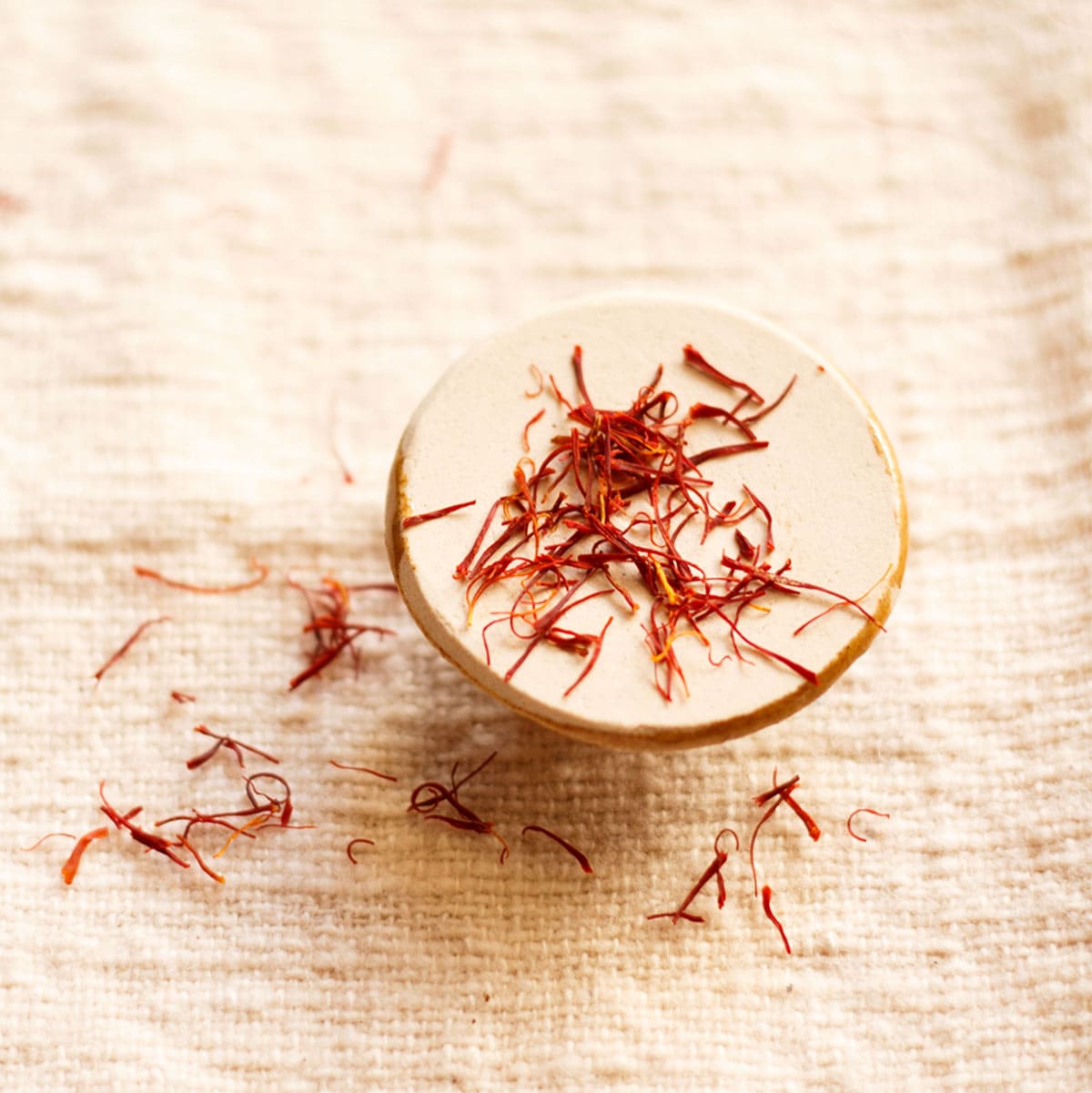 saffron strands on a round beige holder on burlap