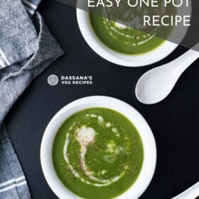 overhead shot of spinach soup topped with coconut cream in two white bowls and two white spoons placed on a black board with text layovers