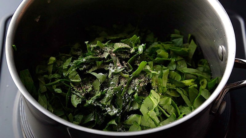 adding freshly chopped spinach and crushed black pepperto the pan