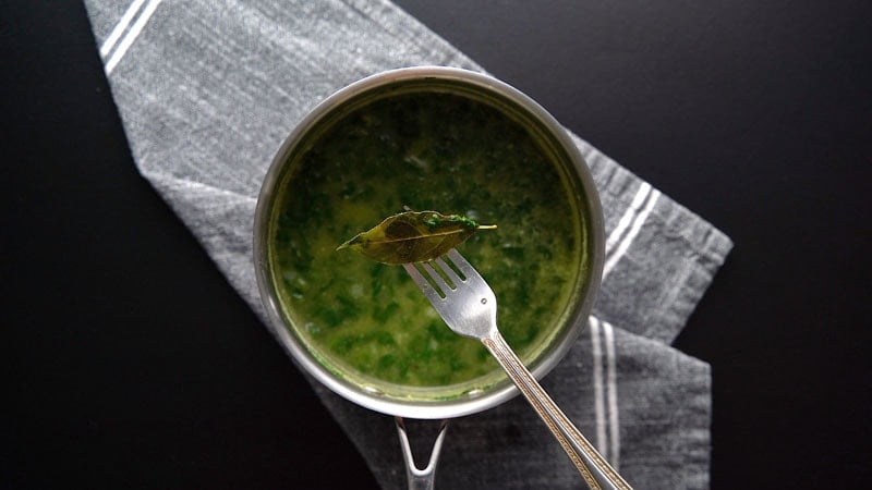 removing bay leaf with a fork from the soup