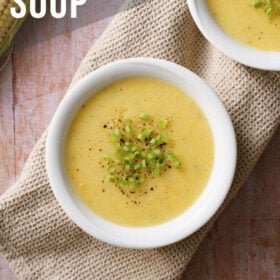 overhead shot of sweet corn soup in white bowl garnished with spring onion greens with text layovers