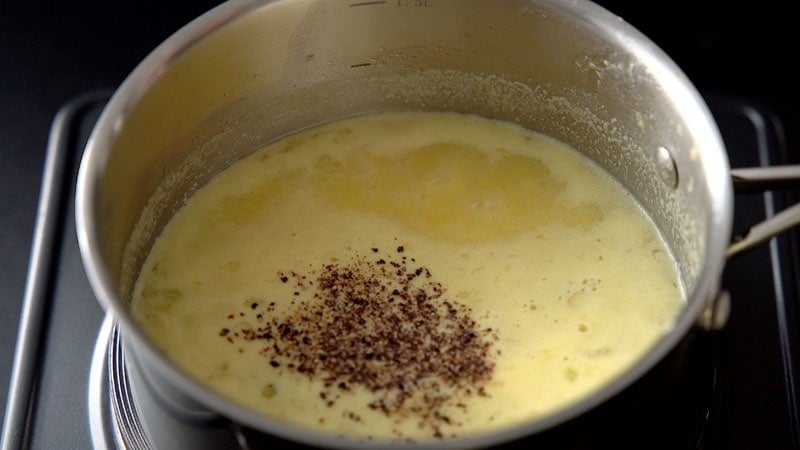 black pepper and salt on sweet corn soup inside the pan