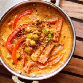 overhead shot of veg kadai in a metal kadai with a white linen on top right side on a wooden board