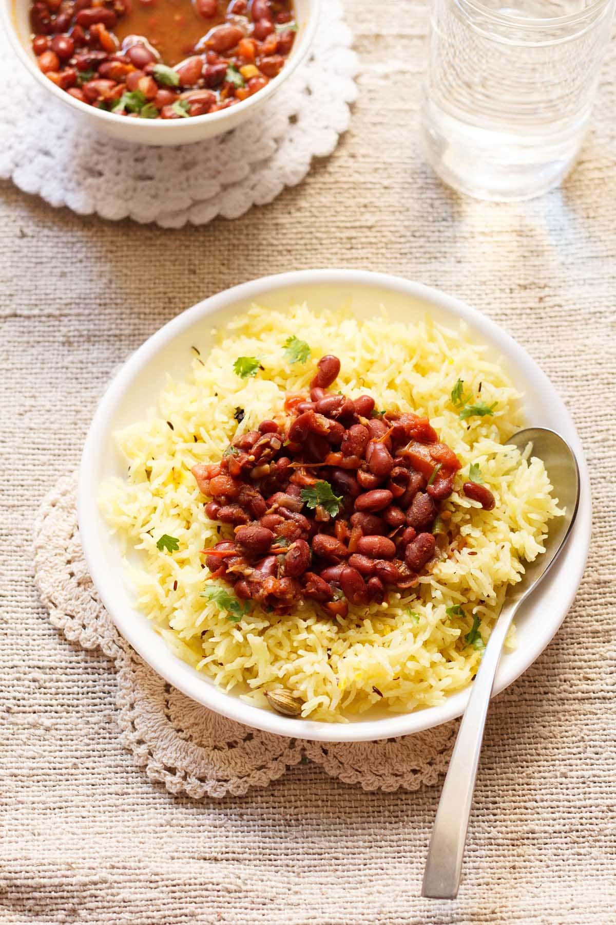 yellow rice on a white plate topped with kidney beans curry