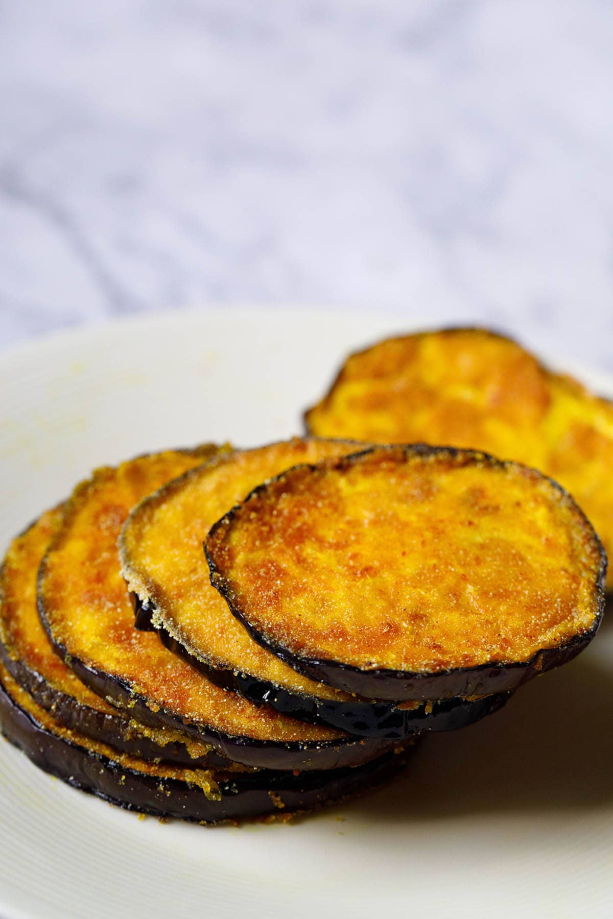 stack of baingan bhaja in a cream colored plate