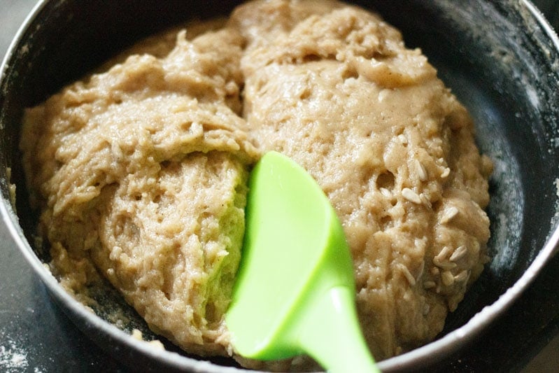 Batter in black bowl with green mixing spoon for eggless banana bread