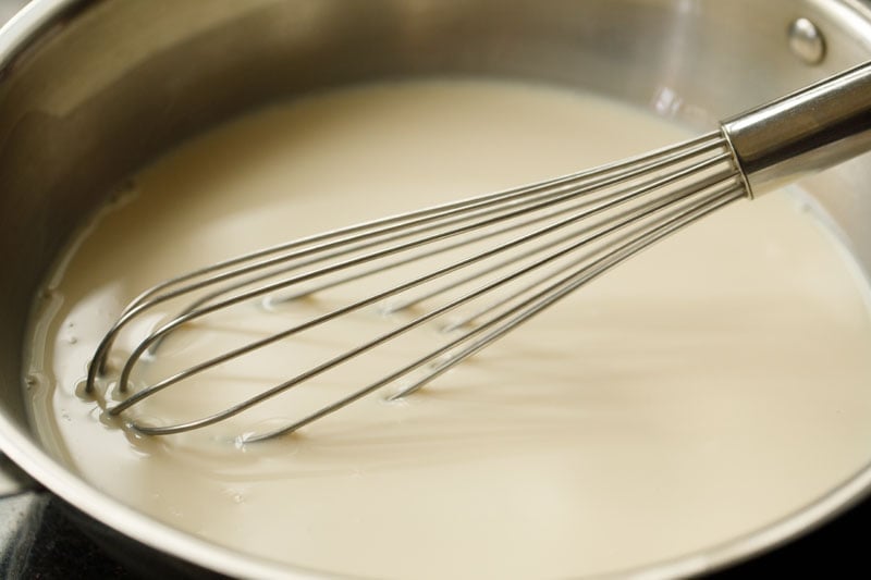 condensed milk and milk being mixed with wired whisk