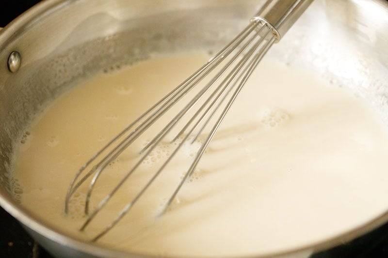 pan filled with milk mixture with wired whisk inside