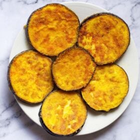 overhead shot of begun bhaja or baingan bhaja slices in a cream colored plate