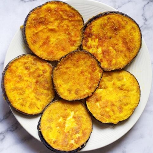 overhead shot of begun bhaja slices in a cream colored plate