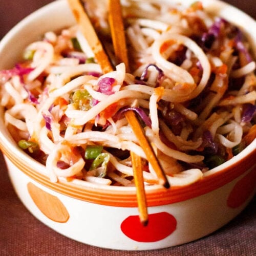 chow mein in an orange and white bowl with a pair of wooden chopsticks