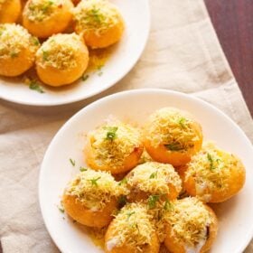 overhead shot of dahi puri in two plates on a beige cotton napkin