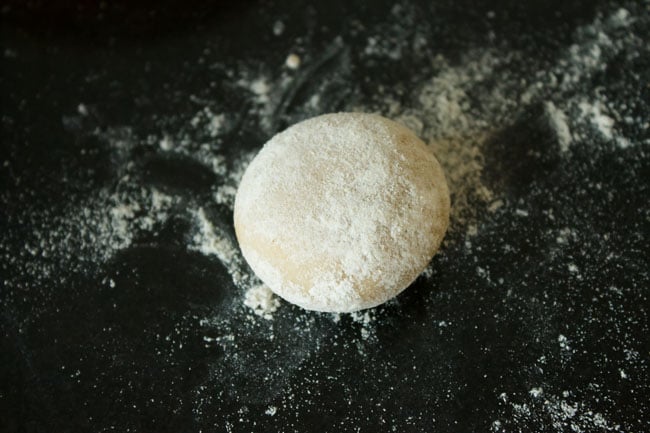 flattened round of dough sprinkled with flour on a flour dusted surface