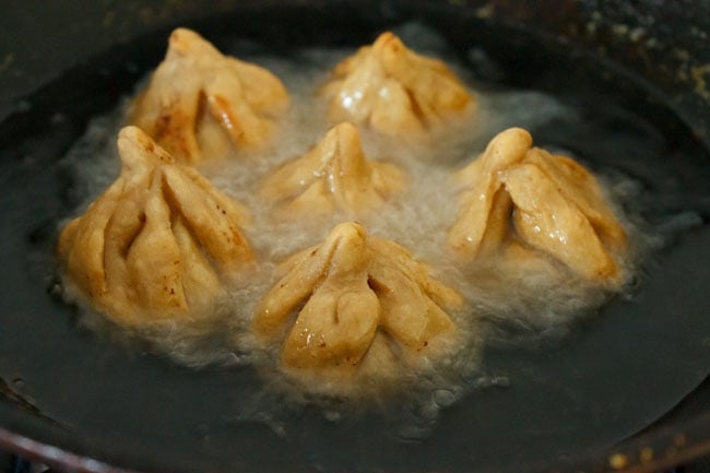 frying modak in hot oil in pan