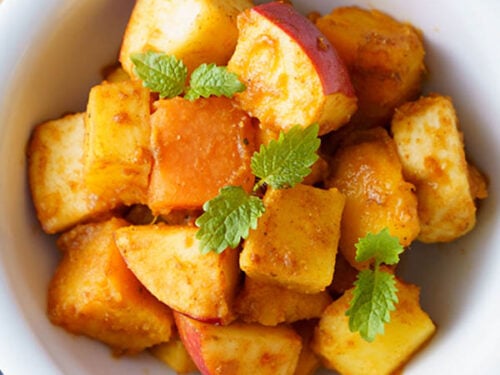 closeup shot of fruit chaat garnished with mint sprigs in white bowls