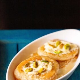 malpua with rabdi served in a oval plate on a dark blue tray