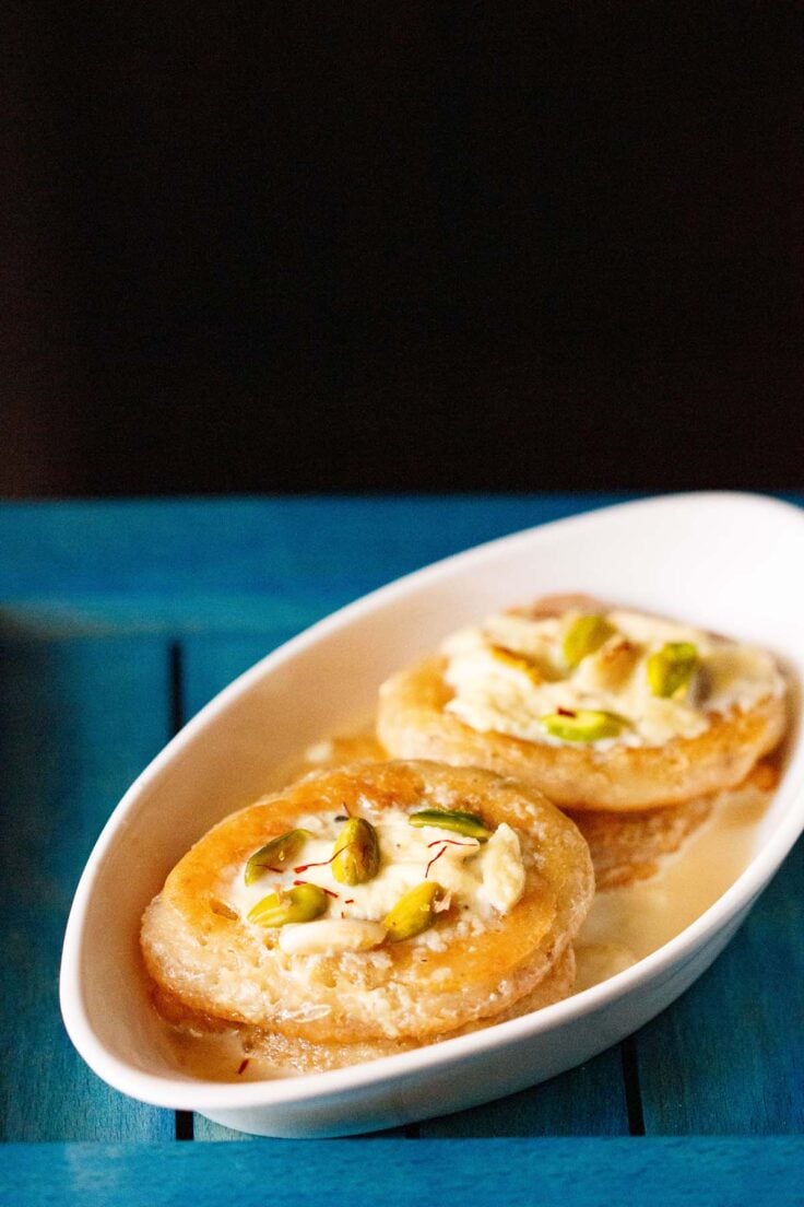 malpua with rabdi served in a oval plate on a dark blue tray