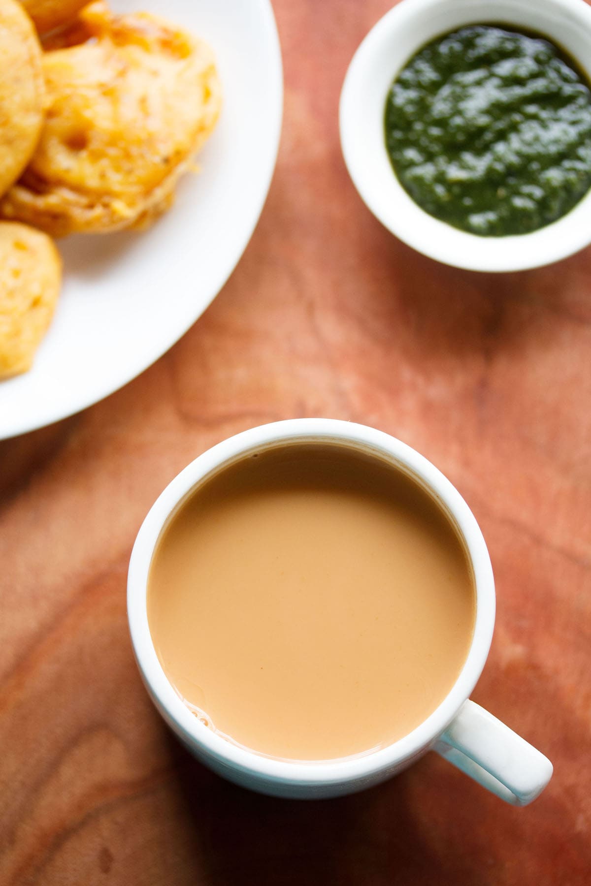 overhead shot of masala teain a white cup on brown board