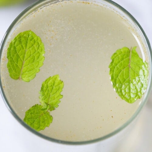 closeup shot of shikanji in a glass with mint leaves
