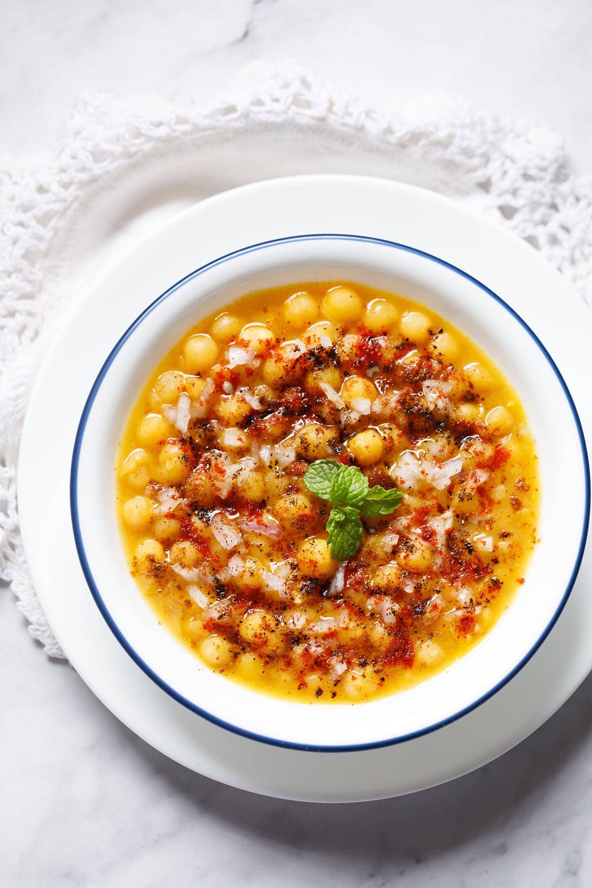 overhead shot of ragda with a ming sprig in center filled in a blue rimmed white bowl